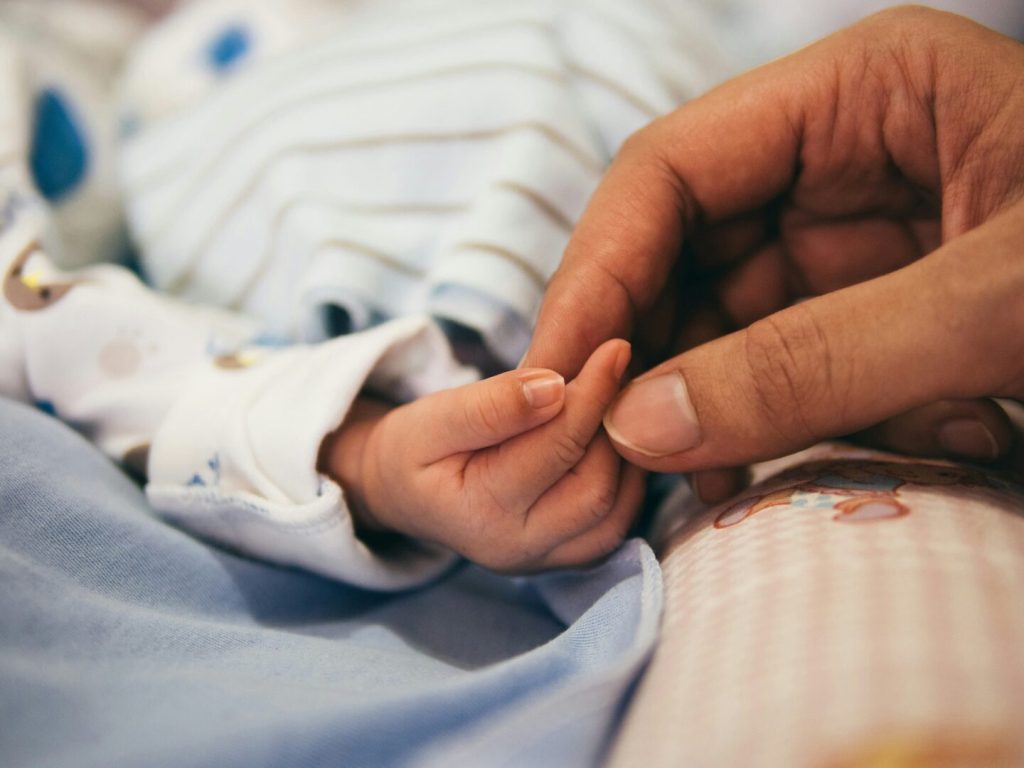 Shahjahanpur, neonata trovata sepolta viva: salvata da un pastore, è morta una settimana dopo Mano di neonato che stringe il dito di un adulto, simbolo di fragilità e protezione