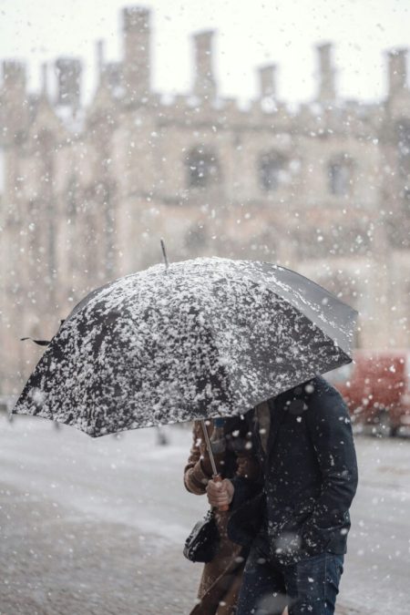 Coppia sotto un ombrello durante una nevicata in città