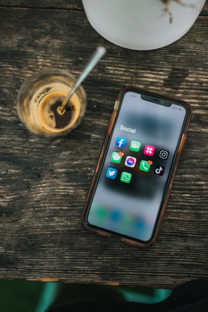 Smartphone con app social su tavolo di legno, simbolo del legame tra social e tecnologia