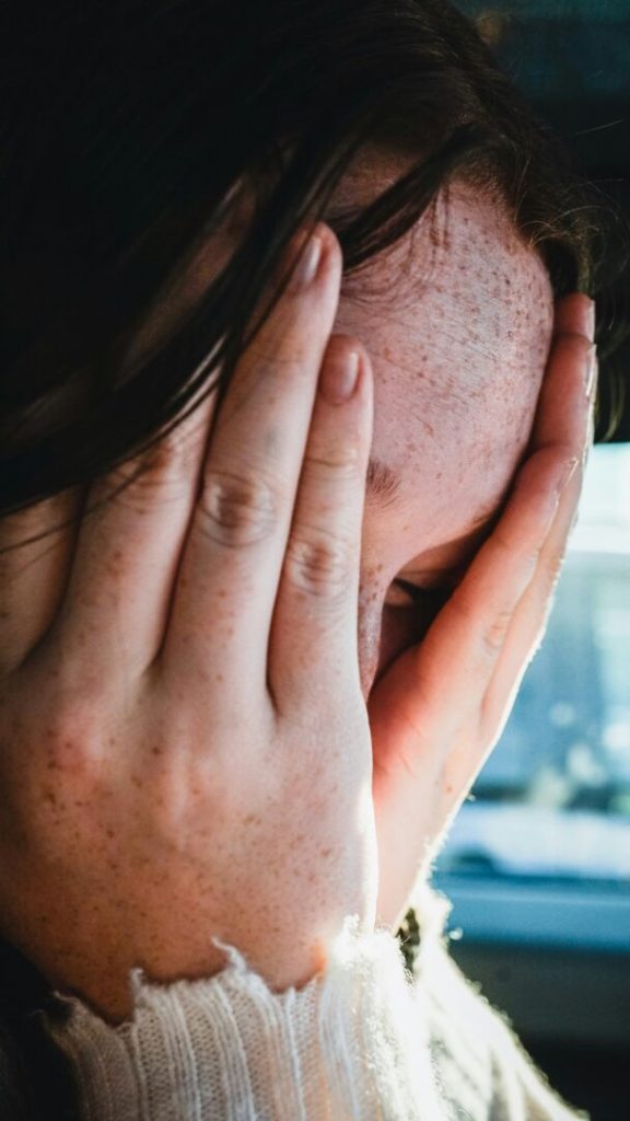 Ragazza adolescente con le mani sul volto dopo episodio di violenza domestica