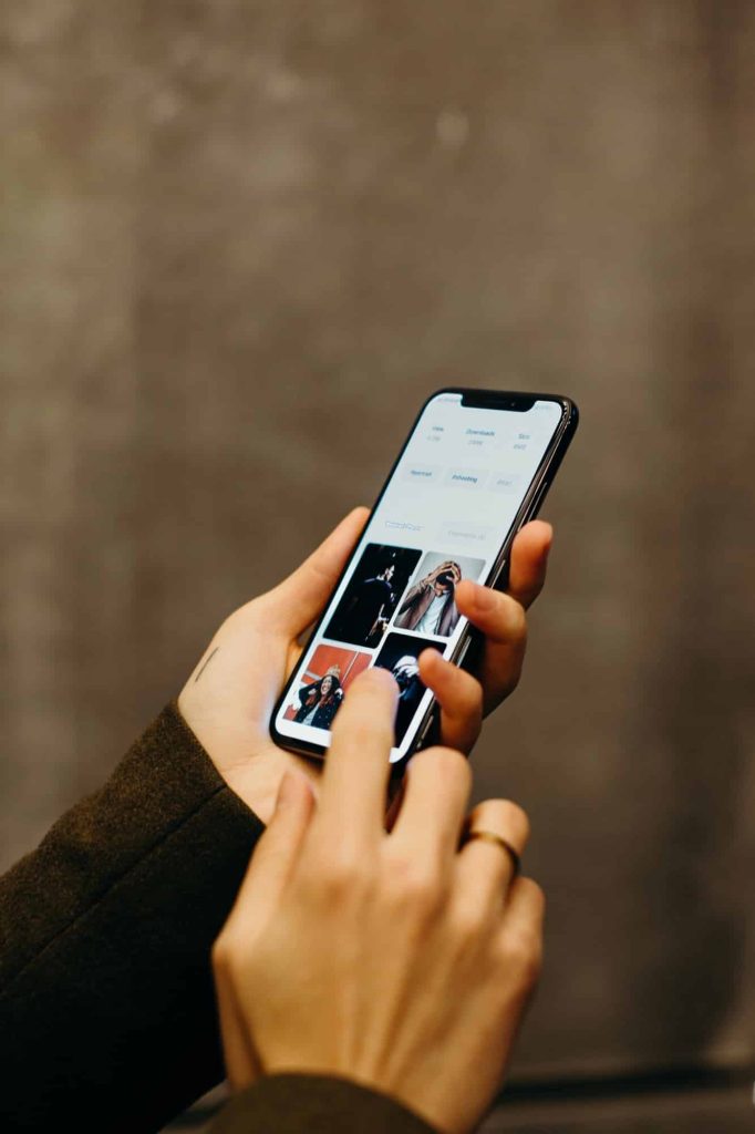 Bellunese, 26enne arrestato per presunti abusi sulla figlia di cinque anni: l’indagine sui video condivisi online Persona che consulta immagini su smartphone moderno