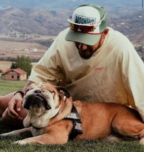 Lewis Hamilton accarezza il suo cane bulldog sdraiato sul prato