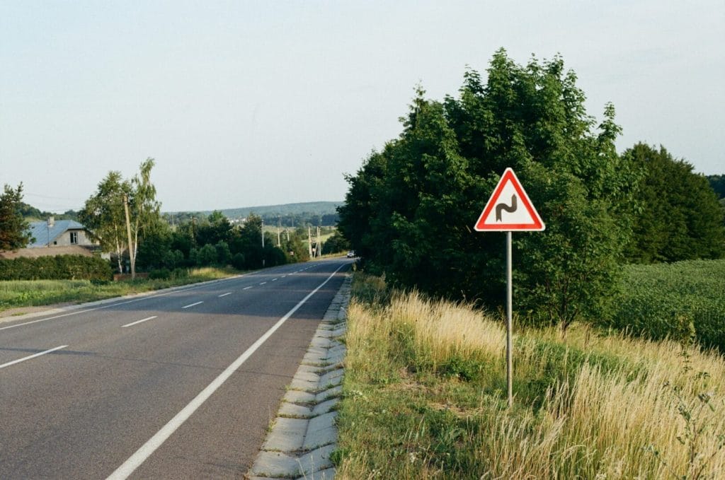 Strada con segnale di curva pericolosa