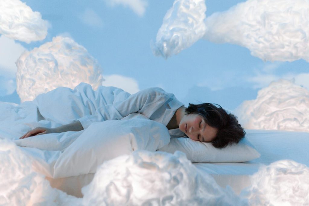 Persona che dorme serenamente tra nuvole bianche, simbolo di sonno rigenerante e qualità del riposo