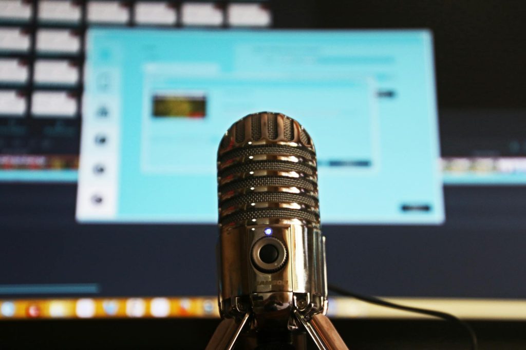 Podcast, il nuovo modo di informarsi: perché nel 2025 sono diventati indispensabili Persone che ascoltano un podcast con cuffie davanti a un microfono
